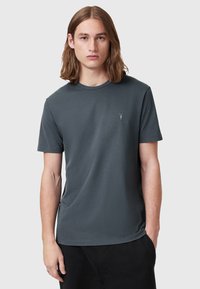 Szara koszulka o okrągłym dekolcie, wykonana z miękkiej bawełny. Posiada krótkie rękawy oraz małe haftowane logo po lewej stronie klatki piersiowej.