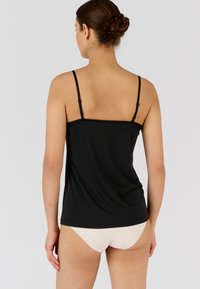 Camisole noire avec des bretelles spaghetti réglables, présentant une texture lisse et une délicate bordure en dentelle le long de l'encolure.