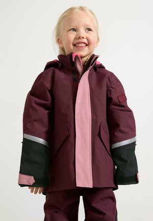 Maroon ja ruusupunainen vettä hylkivä takki hupulla, jossa on heijastinteippejä, mustia yksityiskohtia ja vetoketjulla varustettu etuosa. Sileä rakenne, väljä istuvuus.