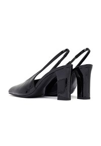 Tacones de charol negro tipo slingback con tacones de bloque, puntas afiladas y un acabado liso y brillante, mostrados uno al lado del otro sobre un fondo blanco.
