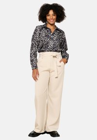 Black and white leopard print shirt with a collar, paired with high-waisted beige wide-leg trousers, featuring a tie belt.