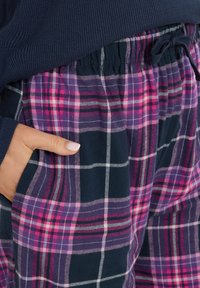 Ruitjes pyjamabroek in navy, paars en roze, met een trekkoord in de taille en zijzak, gemaakt van een zachte, gestructureerde stof.