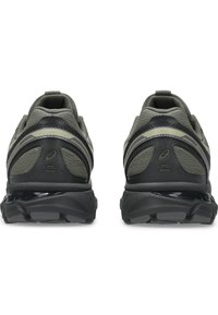 Graue Mesh-Laufschuhe mit schwarzen Akzenten, die eine gepolsterte Sohle und strukturiertes Fersendetail zeigen. Entworfen für Stabilität und Komfort.