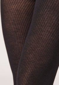Černé žebrované punčocháče s jemnou texturou, zdobené vertikálními pruhy a hladkým povrchem. Detailní pohled, který zdůrazňuje vzor a materiál.