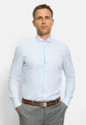 Hellblaues, knöpfbares Hemd mit einem dezent geometrischen Muster, langen Ärmeln und einem Kragen, kombiniert mit grauen Hosen und einem braunen Gürtel.