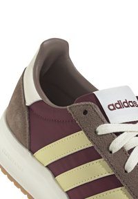 Brun och burgundy träningsskor med gula ränder, tillverkade av mocka och nylon, snörning, vadderad krage och vit branding.