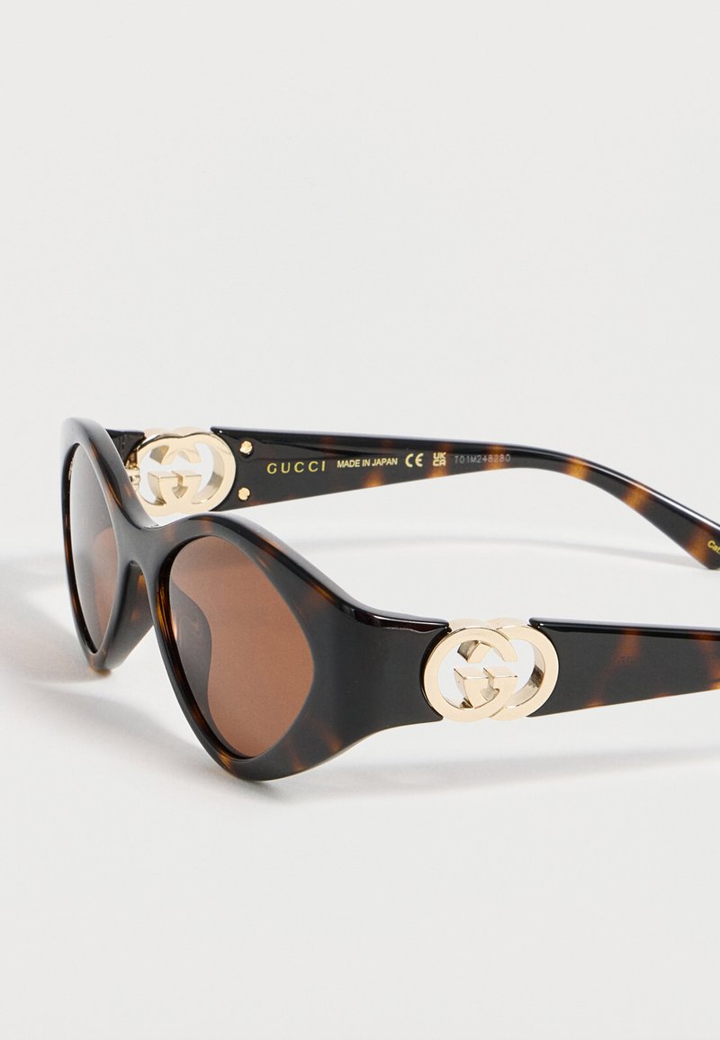 Sonnenbrille im Katzenaugenstil mit Schildpattmuster, dunkelbraunen Gläsern und goldenen Gucci-Logos an den Bügeln, hergestellt in Japan.