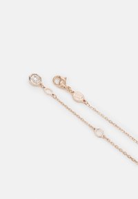 Chaîne en or rose avec des détails octogonaux et un pendentif en pierre précieuse transparente, terminée par un fermoir en homard. Design élégant et délicat.