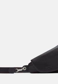 Czarna skórzana torba na ramię z klapką, z teksturowanym paskiem i metalowymi akcentami, prezentująca minimalistyczny design.