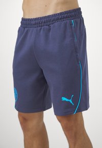 Shorts bleu marine en tissu doux, dotés d'une taille élastique, de poches latérales et d'accents bleu vif le long des coutures et du logo.