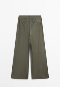 Oliwkowe spodnie z szerokimi nogawkami, z dwoma tylnymi kieszeniami z rozcięciami, paskiem w talii i z przodem z plisą, rozłożone na białym tle.