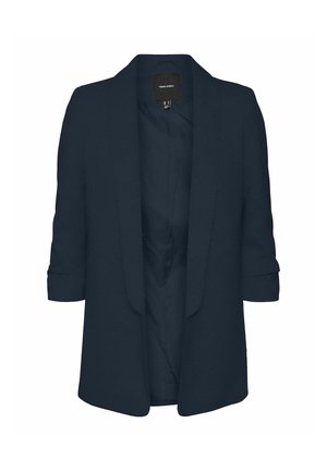 Blazer marine avec une texture lisse, devant ouvert et manches retroussées. Présente un design minimaliste et une étiquette au niveau du col.
