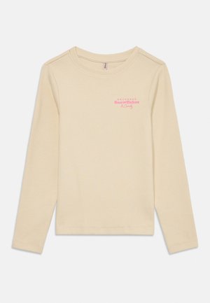 Tricou crem cu mânecă lungă, din material reiat, cu text roz "December Snowflakes & Candy" în partea superioară stângă a pieptului.