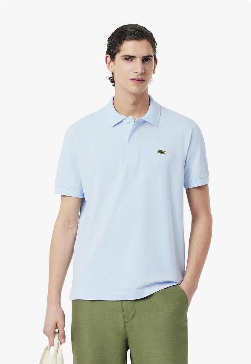 Polo shirt azzurro in cotone, con colletto a due bottoni, maniche corte e logo verde sul lato sinistro del petto.
