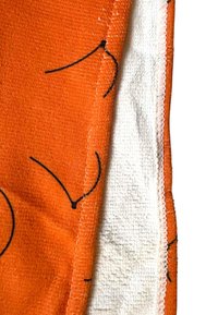 Orange textil med svarta linjemönster, med en mjuk frottéstruktur och en vit, plyschig innerfoder, avslutat med sydda kanter.