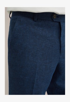 Tumedat püksid, mis on valmistatud tekstuuritud kangast, millel on lame esiosa, küljetaskud ja ühe nupuga sulgemine vööümbruses.