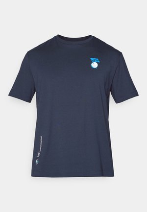 T-shirt en coton bleu marine à manches courtes avec un design de logo bleu sur la poitrine et du texte le long de l'ourlet latéral. Texture lisse.