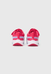Une paire de baskets rouges et violettes avec des semelles blanches vue de l'arrière, montrant des boucles au talon et des semelles texturées sur un fond blanc.