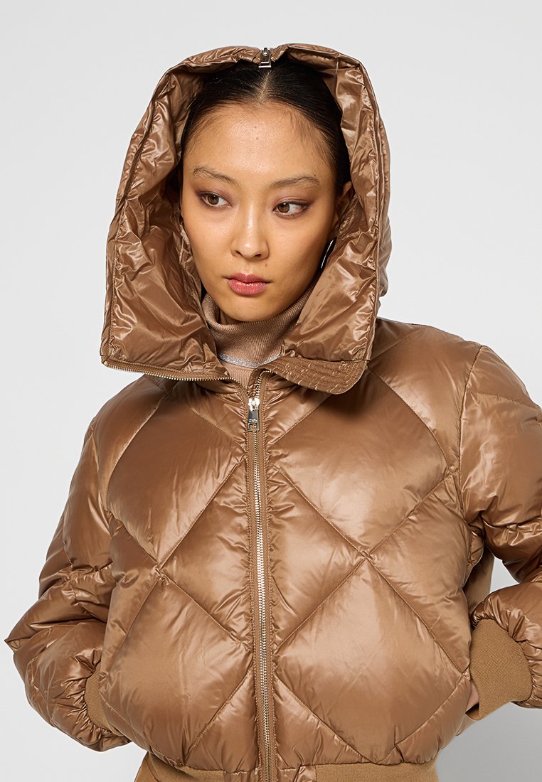 Brązowa puchowa kurtka z diamentowym przeszyciem, wysokim kołnierzem i odpinanym kapturem. Gładki, błyszczący materiał z prążkowanymi mankietami i zamek błyskawiczny z przodu.
