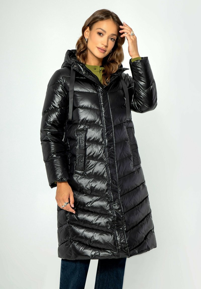 Schwarze Steppjacke mit glänzender Oberfläche, Kapuze und Fronttaschen. Mit horizontaler Steppung und verstellbaren Riemen an der Kapuze.