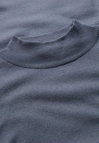 Grijze gebreide trui met een hoge, geribbelde kraag. De stof lijkt zacht met een gladde textuur, en heeft een subtiel, gelijkmatig patroon.