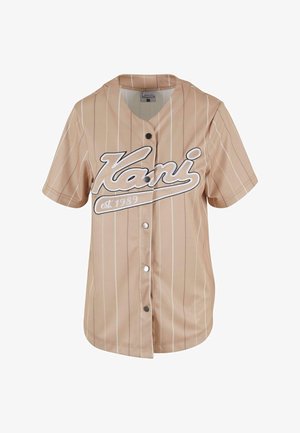 Lühikeste varrukatega beež pesapallijakk, millel on valged vertikaalsed triibud, ees nupud ja rinnaosa "Kani" logo koos asutamise aastaga.