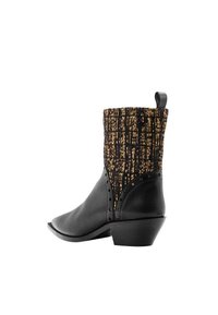Bota de vaquero de cuero negro con un empeine texturizado de tejido dorado y negro, que presenta un tacón bajo y adornos de remaches a lo largo del costado.