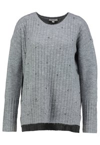 Grå stickad tröja med ribbad struktur, rund halsringning och långa ärmar. Pärlade detaljer genom hela tröjan och en kontrasterande nedre fåll.