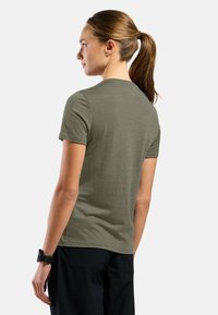 Olive green short-sleeve t-shirt with a crew neckline, made of soft fabric. Worn with dark trousers, showing a relaxed fit and smooth texture.