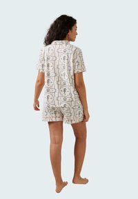 Set di pigiama a maniche corte in tessuto leggero con una stampa ispirata alla natura. Presenta una camicia con colletto e pantaloni corti stampati con bordi a contrasto.
