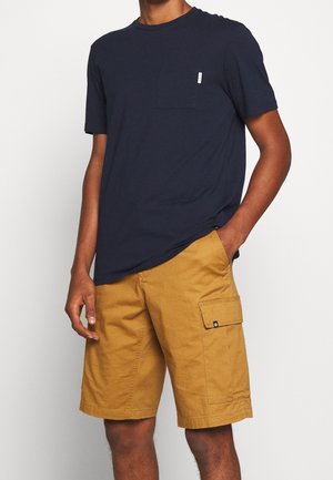 T-shirt à manches courtes bleu marine avec une poche et un short cargo marron avec des poches latérales, fabriqué en coton avec une texture lisse.