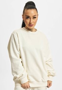 Cremefarvet oversized sweatshirt med rund hals, ribstrikkede manchetter og kant. Blødt stof med en glat struktur og minimal detaljer.