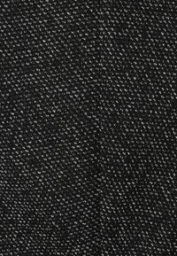 Tissu noir texturé avec un motif fin, présentant des fils blancs éparpillés créant un contraste subtil. Apparence douce et tissée.