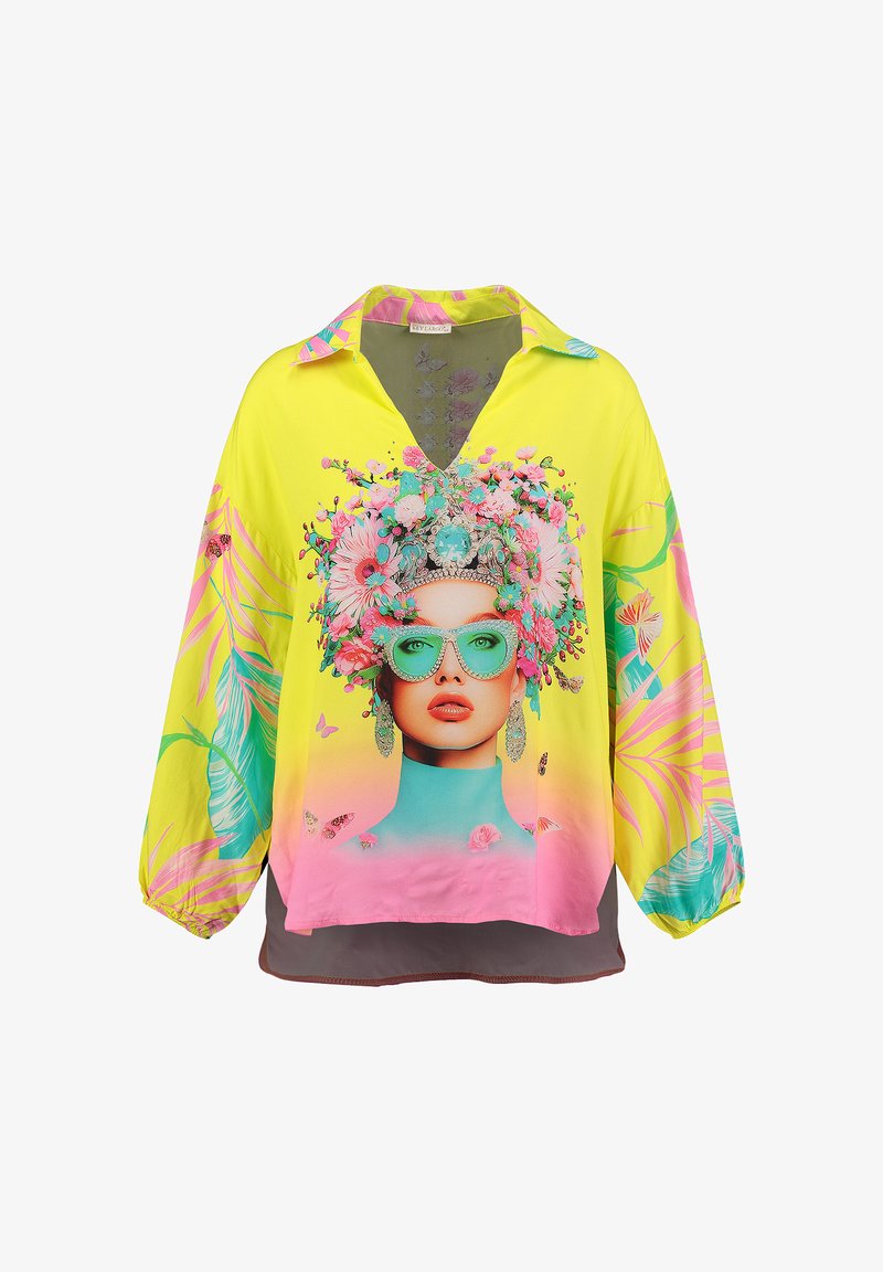 Gelbe Bluse mit einem grafischen Blumen-Gesichtsdruck, der leuchtend pinke und türkisfarbene Akzente enthält, einem V-Ausschnitt und langen Ärmeln.