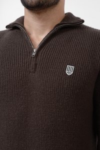 Brun zip-up tröja gjord av strukturerat stickat tyg. Har en fjärdedels dragkedja, hög krage och en liten logotyp på vänster bröst.