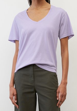 Lavendel V-hals t-shirt van lichtgewicht katoen, korte mouwen, comfortabele pasvorm, gecombineerd met donkergroene broeken, soepele textuur, minimale details.