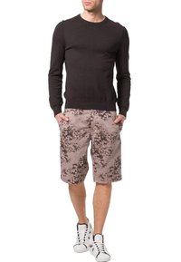 Suéter negro de manga larga combinado con pantalones cortos cargo de estampado floral beige y zapatillas blancas. El conjunto presenta un ajuste casual y relajado.