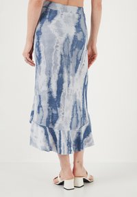 Garšīga zila un balta rakstaina svārka ar izpletni apakšā, izgatavota no tekstūras auduma, ar maigu tie-dye efektu.