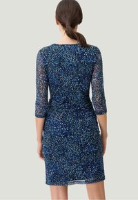 Navy Kleid mit einem mehrfarbigen, gesprenkelten Muster, transparenten 3/4-Ärmeln, taillierter Form und knielangem Saum.