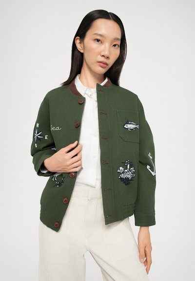 Chaqueta de algodón verde con acentos marrones, cierres de botón y diseños náuticos bordados que incluyen peces y un ancla.