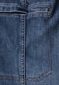 Abschnitt aus Denim-Stoff mit einer hinteren Tasche und sichtbaren Nähten. Hellblaue Farbe mit weicher Textur und leicht ausgewaschenem Design.