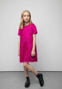 Różowa sukienka z krótkim rękawem wykonana z teksturowanego, puszystego materiału. Połączona z czarnymi, teksturowanymi butami i ciemnymi skarpetami. Prosty i nowoczesny design.