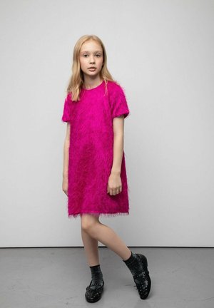 Różowa sukienka z krótkim rękawem wykonana z teksturowanego, puszystego materiału. Połączona z czarnymi, teksturowanymi butami i ciemnymi skarpetami. Prosty i nowoczesny design.