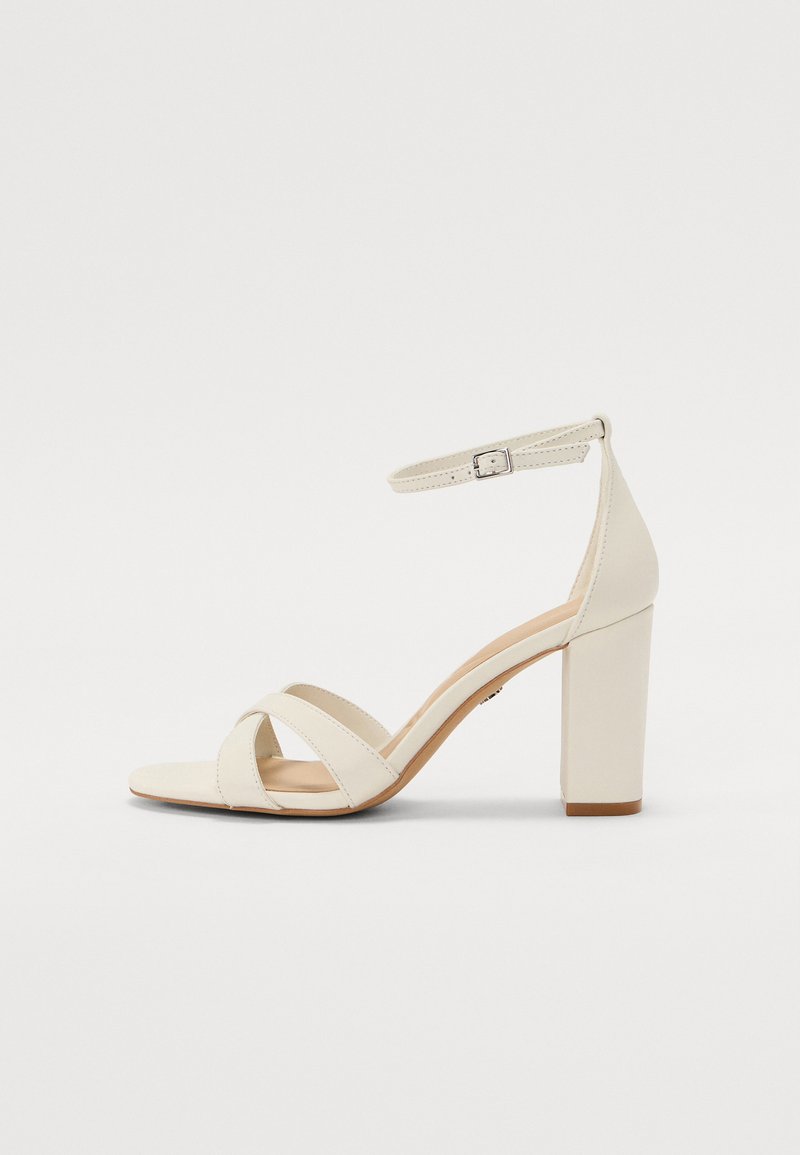 Sandal con tacco color crema, con punta quadrata, cinturini incrociati, cinturino alla caviglia con fibbia e tacco largo. Texture in pelle liscia.