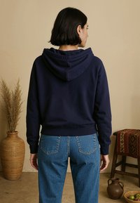 Marineblauwe hoodie met een losse pasvorm, van katoen, met ribgebreide manchetten en tailleband, gecombineerd met lichtdenim jeans.