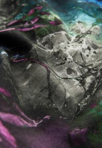 Farbenfroher Schal mit einer Mischung aus schwarzen, lila und grünen abstrakten Blumenmustern auf weichem, strukturiertem Stoff mit einem fließenden Fall.