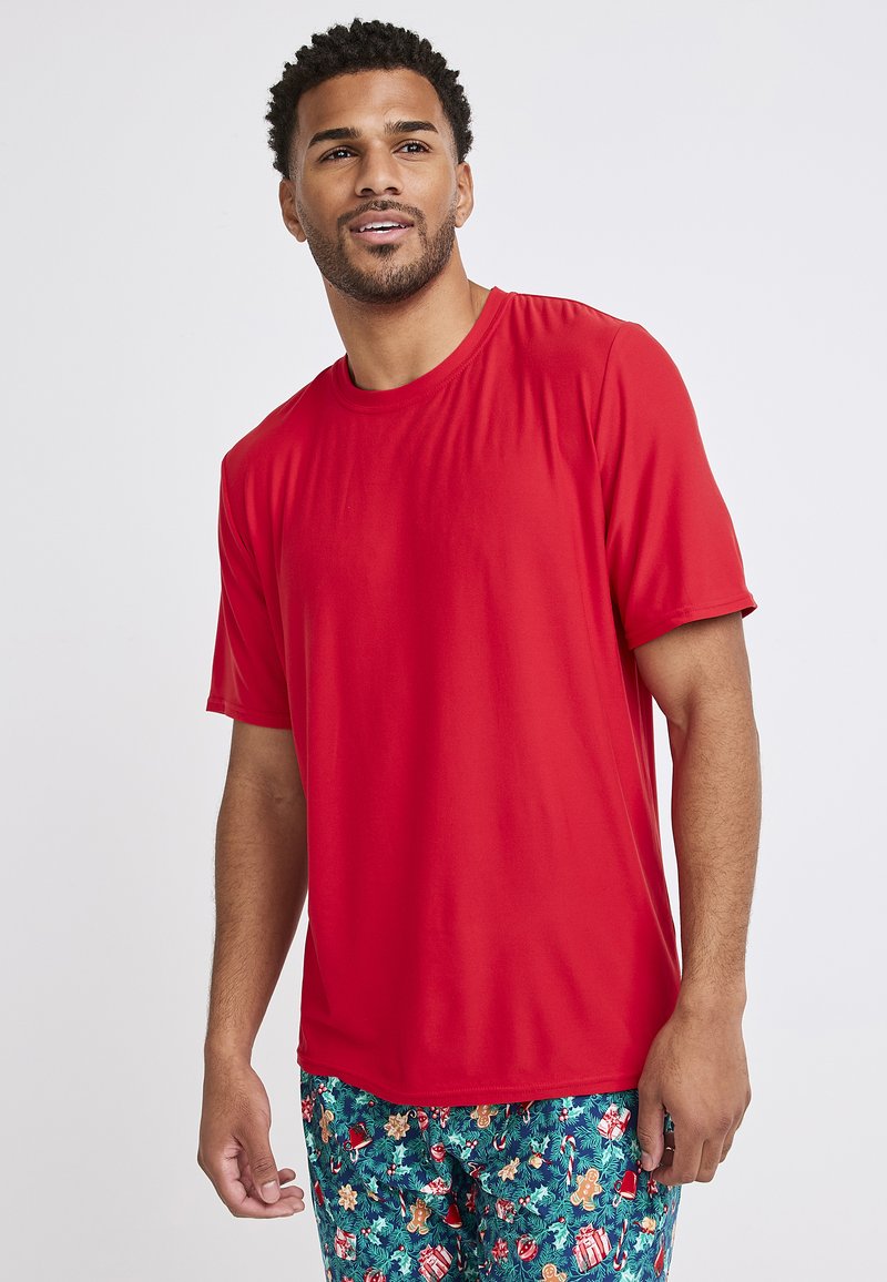 Czerwona koszulka z krótkim rękawem, wykonana z lekkiego materiału o gładkiej fakturze. Posiada klasyczny okrągły dekolt i luźny krój. W zestawie z wzorzystymi szortami.