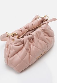 Quiltrad rosa läderhandväska med dragkedjeslutning och guldfärgad beslag. Har en mjuk, rundad form och ett knutet handtag för bärande.