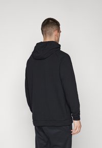 Sweat à capuche noir en mélange de coton, avec une coupe décontractée, des poignets côtelés et une poche kangourou. Texture lisse.