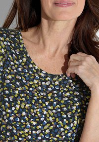 Bloemmotief top in donkere stof met kleine, meerkleurige bloemetjes in blauw, groen, geel en beige. Ronde halslijn, korte mouwen.